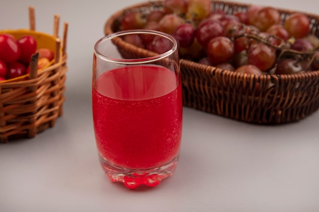 Bezpłatne zdjęcie widok z góry świeżego soku z derenia wiśniowego w szklance z winogronami na wiadrze na szarej ścianie