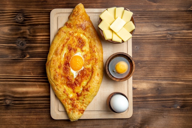 Widok z góry Świeżo upieczony chleb z gotowanym jajkiem na brązowym drewnianym biurku chleb ciasto mąka bułka śniadanie jajko