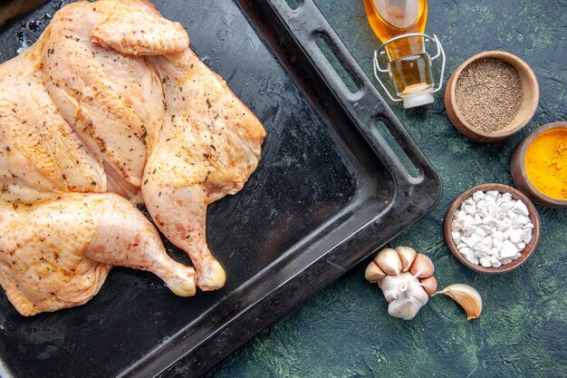 Widok z góry świeży przyprawiony kurczak z przyprawami na ciemnoniebieskim stole jedzenie przyprawa pieprz danie obiad kolor mięsa sól do pieczenia