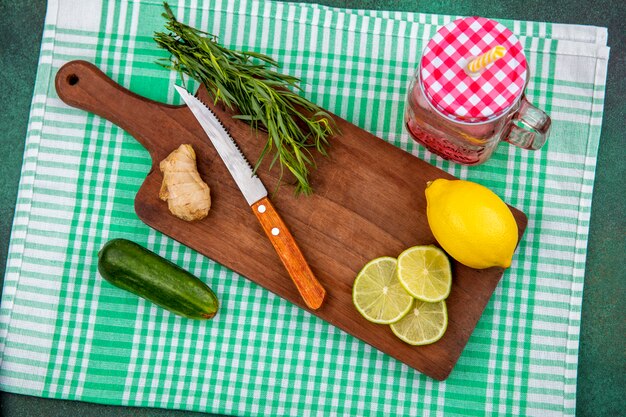 Widok z góry świeżych cytryn na drewnianej kuchni szerokiej z zieleniną estragonu z nożem na zielonym obrusie w kratkę