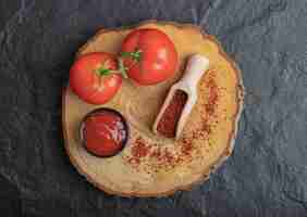 Bezpłatne zdjęcie widok z góry świeżych dojrzałych pomidorów z keczupem i pieprzem na desce na czarnym tle.