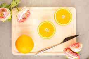 Bezpłatne zdjęcie widok z góry świeżych pomarańczy, kwaśnych, dojrzałych, pokrojonych w plastry i pełnych łagodnych cytrusów tropikalnych z suszonymi różami w kolorze witaminowo-żółtym na kremowym biurku
