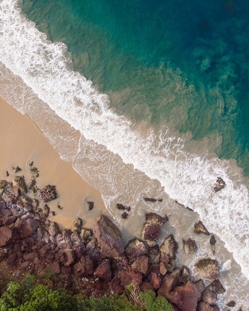 Widok z góry ujęcia fal piany uderzających w skaliste wybrzeże plaży Varkala