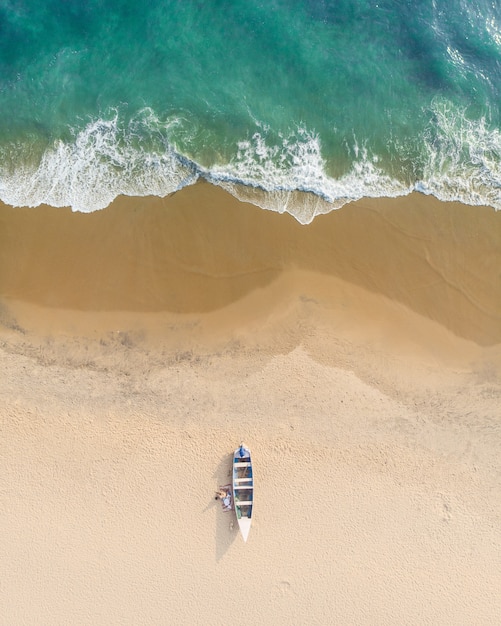 Widok z góry ujęcia ludzi w pobliżu łodzi na piasku plaży Varkala