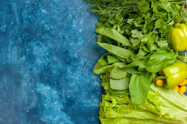 Widok z góry zielone warzywa pietruszka koperek papryka sałata cumcuat na niebieskim tle