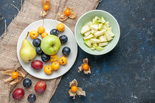 widok z góry zielonych jabłek soczyste i soczyste z pokrojonym jabłkiem wewnątrz talerza z innymi owocami na ciemnoniebieskim biurku, owoce świeża żywność zdrowie witamina