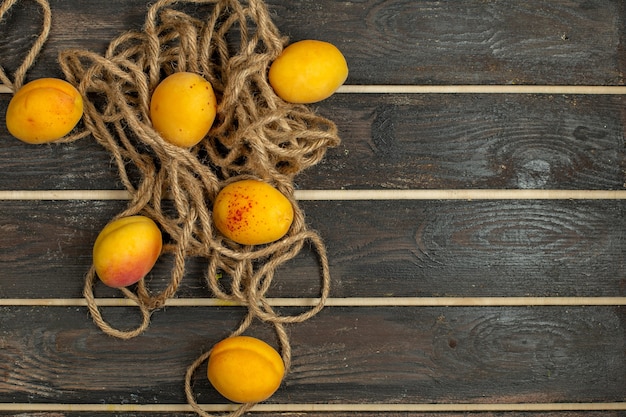 Bezpłatne zdjęcie widok z góry żółte morele łagodne i świeże owoce na rustykalnym biurku