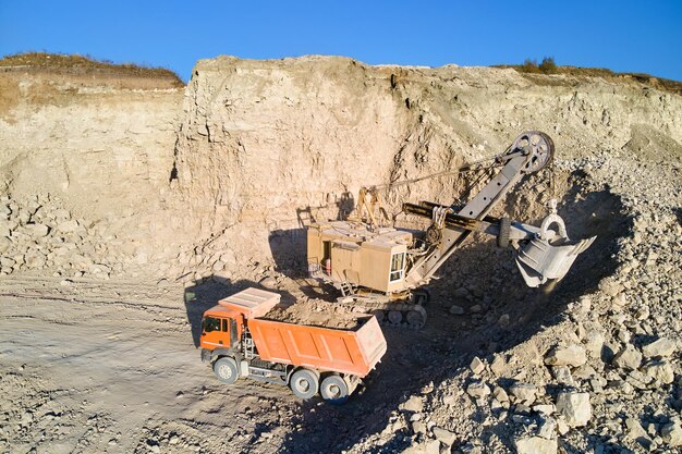Widok z lotu ptaka kopalni odkrywkowej materiałów z piaskowca dla budownictwa z koparką ładującą wywrotkę z kamieniami. koncepcja ciężkiego sprzętu w górnictwie i produkcji użytecznych minerałów