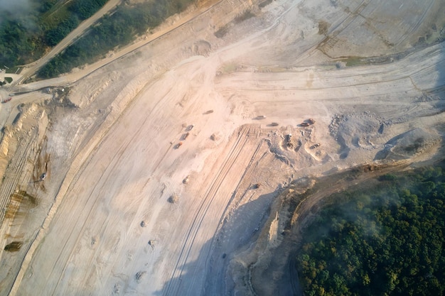 Widok z lotu ptaka kopalni odkrywkowej wydobycia materiałów wapiennych dla przemysłu budowlanego za pomocą koparek i wywrotek.