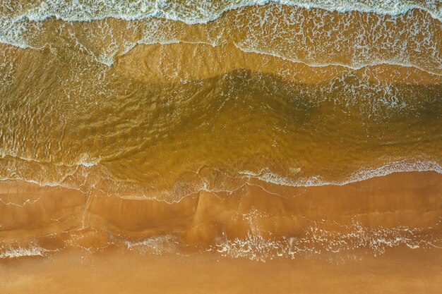 Widok z lotu ptaka na falę oceaniczną docierającą do linii brzegowej