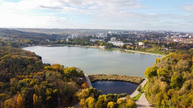 Widok z lotu ptaka na jezioro Valea Morilor w Kiszyniowie. Wiele zielonych drzew, budynki mieszkalne, wzgórza. Moldova