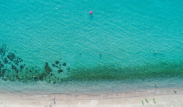 Widok z lotu ptaka na piaszczystą plażę z pływającymi turystami.