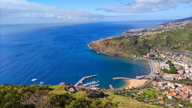 Widok z lotu ptaka na plażę z zielonymi górami i budynkami Machico Madeira