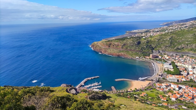 Widok z lotu ptaka na plażę z zielonymi górami i budynkami Machico Madeira