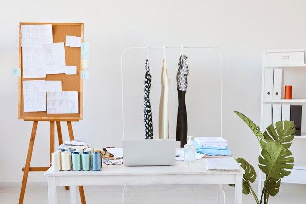 Widok z przodu atelier mody z tablicą pomysłów i biurkiem z linią ubrań