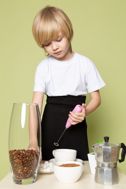 Bezpłatne zdjęcie widok z przodu blondynka chłopiec przygotowuje kawowy napój na stole na kamiennej kolorowej przestrzeni
