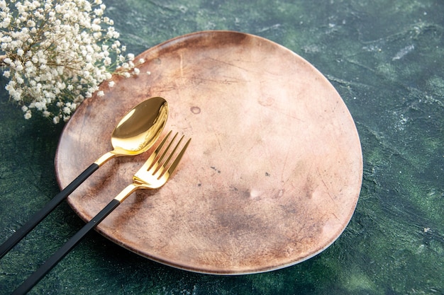 widok z przodu brązowy talerz ze złotą łyżką i widelcem na ciemnym tle
