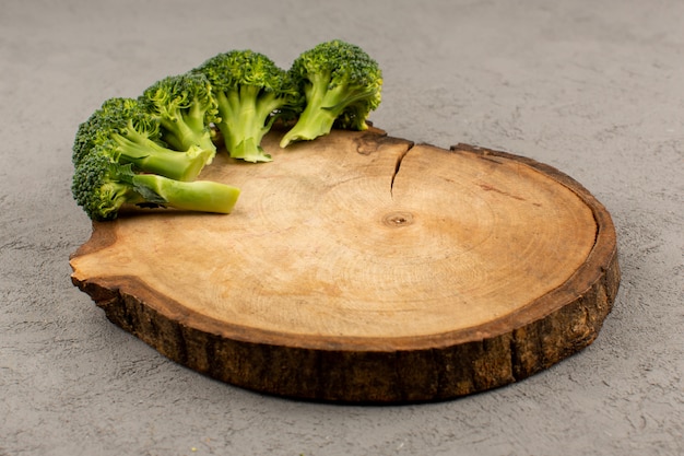 Bezpłatne zdjęcie widok z przodu brokuły zielone świeże dojrzałe na brązowym drewnianym biurku i szarym tle