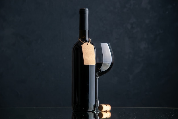 Widok z przodu butelek wina z lampką wina na ciemnej powierzchni
