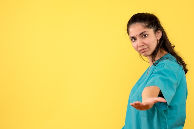 Bezpłatne zdjęcie widok z przodu całkiem kobiet lekarza, podając rękę na żółtej ścianie