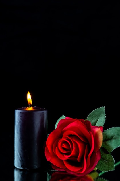 Widok z przodu ciemnej świecy z czerwoną różą na ciemnej powierzchni