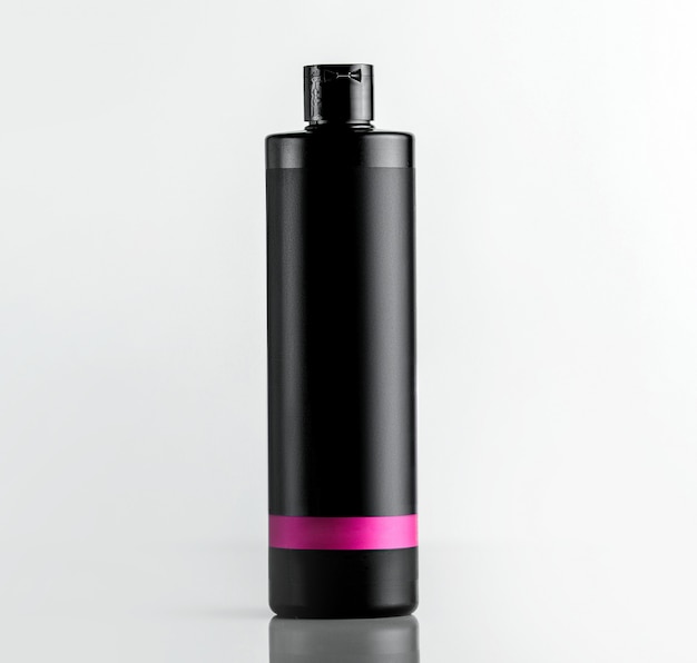 Widok z przodu czarnej plastikowej butelki spod szamponu z różowym paskiem