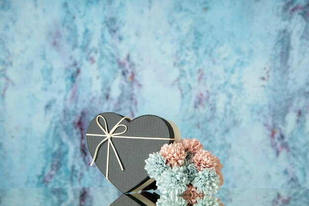Widok z przodu czarnych kwiatów w kształcie pudełka w kształcie serca odbitych na lustrze z niebieskim