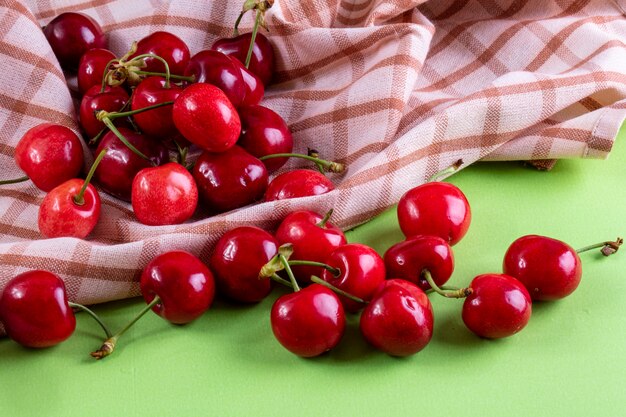 Widok z przodu czerwona wiśnia z ręcznikiem kuchennym na jasnozielonym