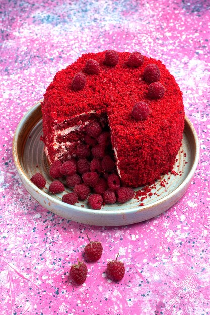 Widok z przodu czerwone ciasto malinowe upieczone pyszne wewnątrz płyty na różowym biurku.