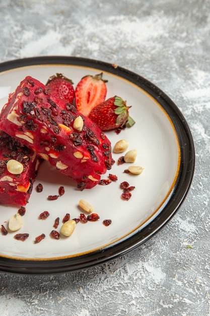 Widok z przodu czerwony nugat pokrojony w orzechy i świeże czerwone truskawki na białej powierzchni słodki deser ciasto orzechowo-orzechowe herbatniki