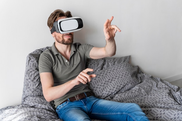 Bezpłatne zdjęcie widok z przodu człowieka za pomocą zestawu słuchawkowego wirtualnej rzeczywistości w łóżku