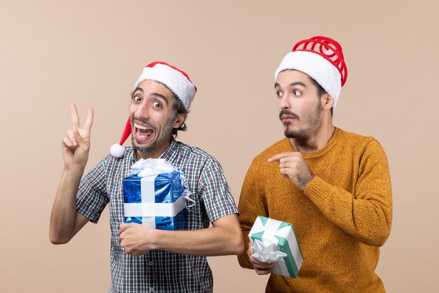 Widok z przodu dwóch facetów, jeden pokazuje znak pokoju zwycięstwa, drugi mylące trzyma prezenty świąteczne