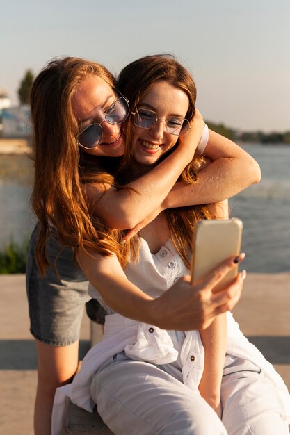 Widok z przodu dwóch kobiet robiących selfie nad jeziorem