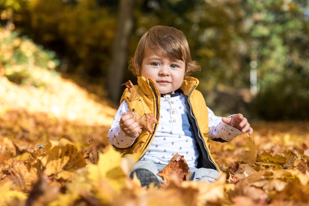 Bezpłatne zdjęcie widok z przodu dziecko siedzi w liściach
