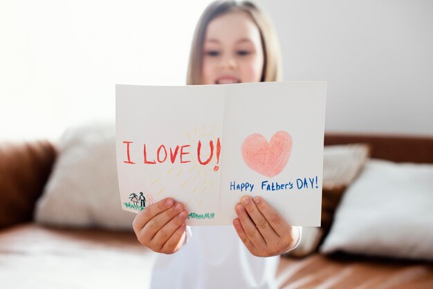 Widok z przodu dziewczynki trzymającej kartkę dnia ojca jako niespodziankę dla jej taty