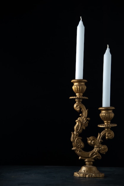 Widok z przodu eleganckiego świecznika z białymi świecami na ciemnym