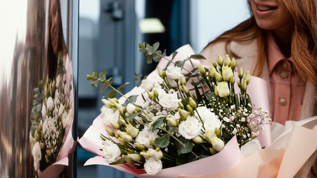 Widok z przodu eleganckiej kobiety z bukietem kwiatów na zewnątrz
