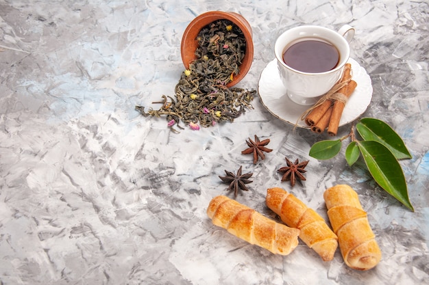 Bezpłatne zdjęcie widok z przodu filiżanka herbaty z bułeczkami na białym stole z ciastem herbacianym