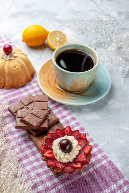 Widok z przodu filiżanka herbaty z ciastem cytrynowym i batonami czekoladowymi na białym biurku ciasto słodka czekolada z cukrem
