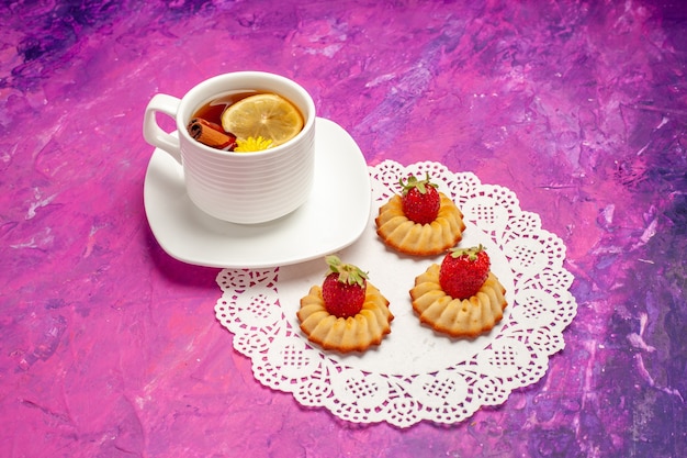 Widok z przodu filiżanka herbaty z herbatnikami na różowym stole w kolorze cukierków z cytryną