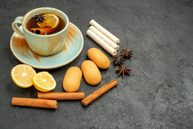 Widok z przodu filiżankę herbaty z cytryną i ciasteczka na szarej tabeli herbatniki słodkie ciasteczka