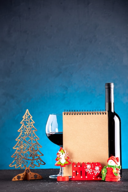 Widok z przodu kieliszek do wina i notatnik do dekoracji świątecznych butelek na jasnoniebieskim tle
