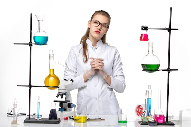 Widok z przodu kobieta chemik w kombinezonie medycznym stojąca z roztworami na białym tle chemia wirus pandemiczny covid-