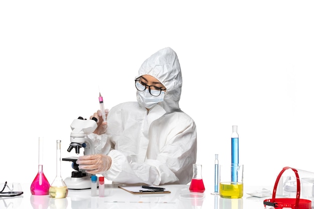 Bezpłatne zdjęcie widok z przodu kobieta chemik w specjalnym kombinezonie ochronnym pracującym z zastrzykami na białym tle laboratorium wirusów chemii covid