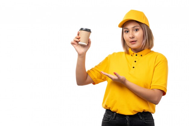 Widok z przodu kobieta kurier w żółtej koszuli, żółtej czapce i czarnych dżinsach, trzymając filiżankę kawy na białym tle