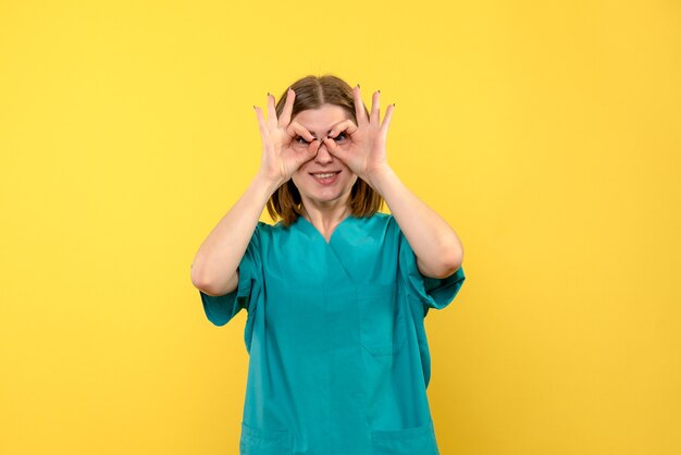 Widok z przodu kobieta lekarz patrząc przez palce na żółtej przestrzeni