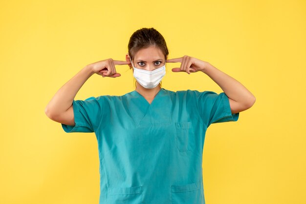 Widok z przodu kobieta lekarz w koszuli medycznej i masce na żółtym tle