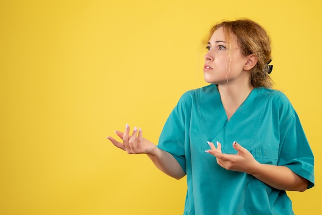 Widok z przodu kobieta lekarz w koszuli medycznej na żółtym biurku pielęgniarka medyczna zdrowia covid-19 kolor