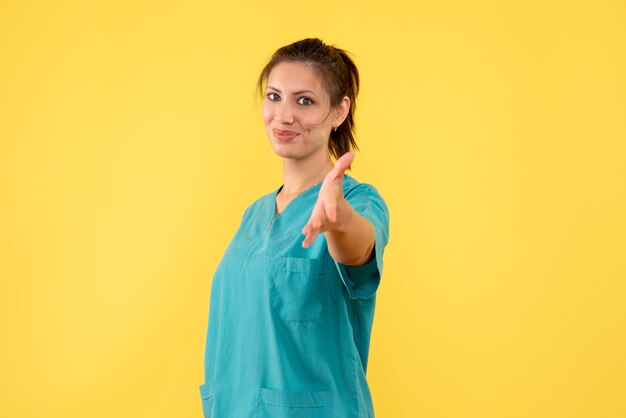 Widok z przodu kobieta lekarz w koszuli medycznej na żółtym tle