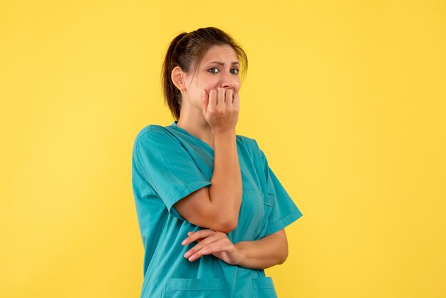 Widok z przodu kobieta lekarz w koszuli medycznej przestraszony na żółtym tle
